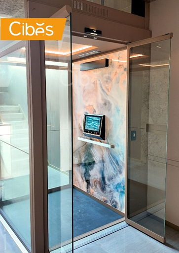 Cibes glass home lift with marble pattern wall panel and touchscreen control matching a luxury home interior.